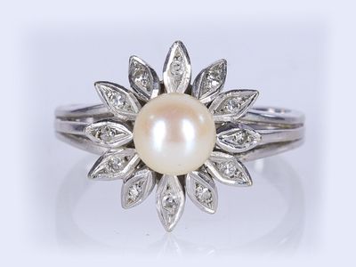 gros plan d'une bague en perles et diamants sur fond blanc