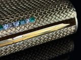 a gold case with diamonds and emeralds on it