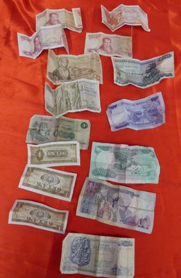 several bills are laid out on a red cloth on a table