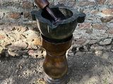un mortier et un pilon posés par terre près d'un mur de briques