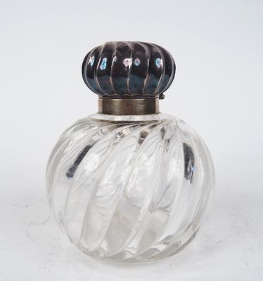 une bouteille en verre avec un bouchon métallique posée sur une surface blanche