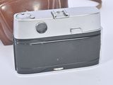 a brown bag and a silver camera on a white surface