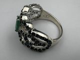 an image of a silver ring with black and green stones on it