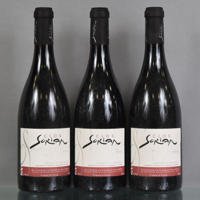 Trois bouteilles de vin sont alignées sur une table en verre