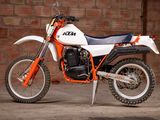 a white and orange dirt bike parked in front of a brick wall