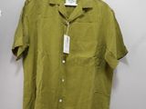 a green shirt hanging on a wall next to a hanger