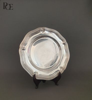 un plat ancien en argent posé sur un socle, sur fond gris