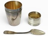 une tasse en argent avec une cuillère et un repose-cuillère à côté