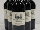 four bottles of red wine are lined up on a white surface