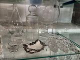 une étagère en verre sur laquelle sont posés de nombreux objets en verre