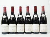 six bouteilles de vin sont alignées sur une surface blanche