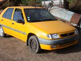 a yellow car that is parked next to a pile of junk