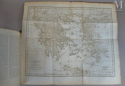 une vieille carte du monde posée sur une table, à côté d'un livre ouvert