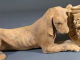 a statue of a dog that is laying down next to a vase