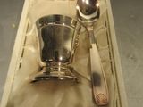 une cuillère en argent et un repose-cuillère dans une boîte