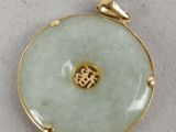 a close up of a green jade pendant with a gold plated clasp