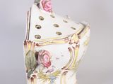 a white vase with pink flowers on it on a table