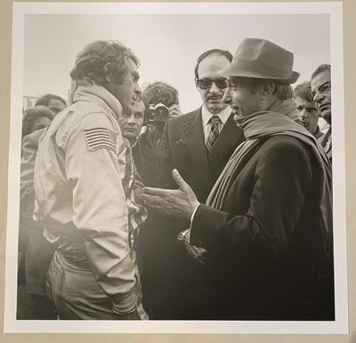 black and white photograph of two men talking to each other in front of a crowd