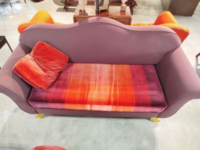 un canapé violet orné de coussins orange dans un salon