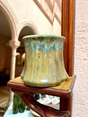 un vase vert posé sur une étagère en bois