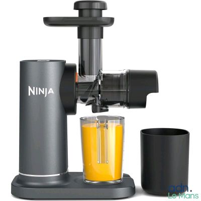 un extracteur de jus, avec un verre de jus d'orange à côté