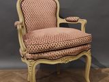 une chaise rose posée sur un parquet, près d'un mur gris