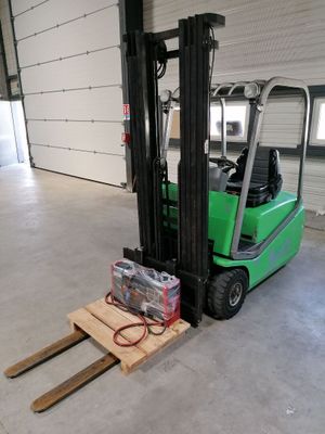 un chariot élévateur vert garé à l'intérieur d'un bâtiment