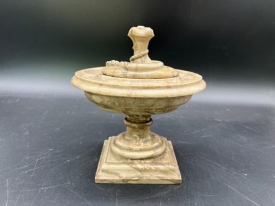 une urne ancienne en pierre sculptée, surmontée d'un oiseau