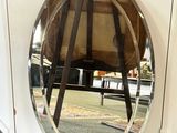 un miroir rond posé par terre à côté d'une chaise