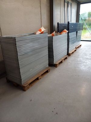 de nombreuses piles de tôles empilées sur des palettes dans un entrepôt