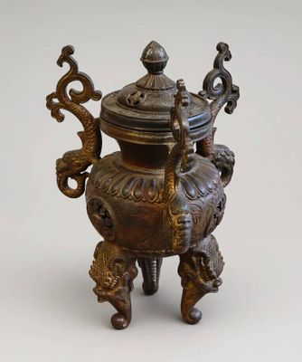 une petite urne en bronze avec un couvercle, posée sur un socle