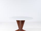 une table ronde avec un piètement en bois et un plateau blanc