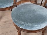 four chairs with blue velvet upholstered seats on a wooden floor