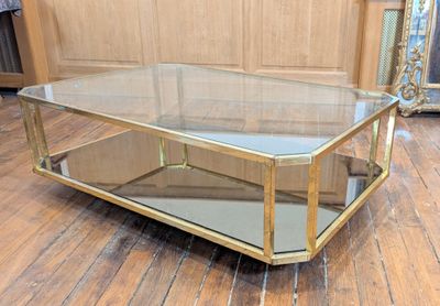 a glass coffee table with a gold frame on it
