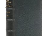 un vieux livre à la couverture noire posé sur une surface blanche