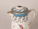 a white coffee pot with a blue lid and flowers on it