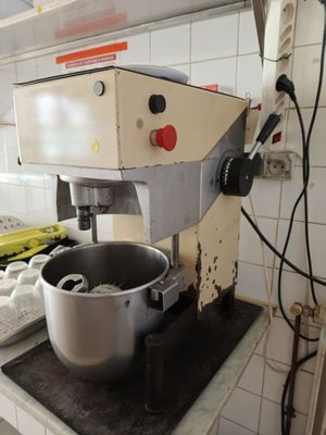a mixer on a counter in a kitchen with a lot of clutter