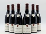 six bouteilles de vin sont alignées sur une surface blanche