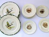 several plates with birds and animals painted on them sitting on a table