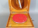 un vieux tourne-disque en bois avec un disque rouge dans un coffret en bois