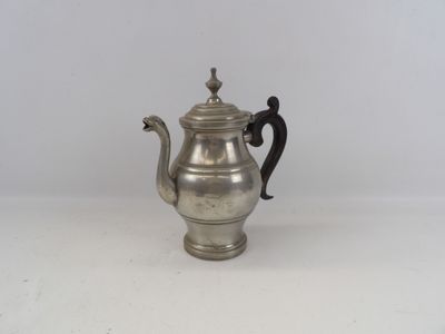 une théière ancienne en argent, dotée d'une anse, posée sur une surface blanche