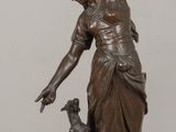 bronze statue of a woman and a dog on a wooden table