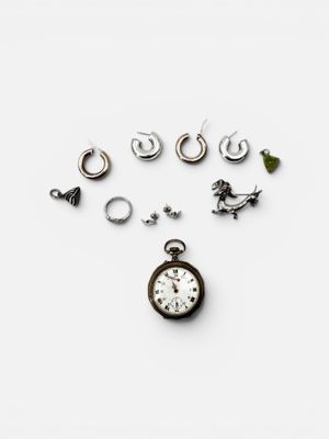 many different types of earrings and a watch on the table