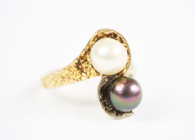 a close up of a pearl and gold ring on a white surface