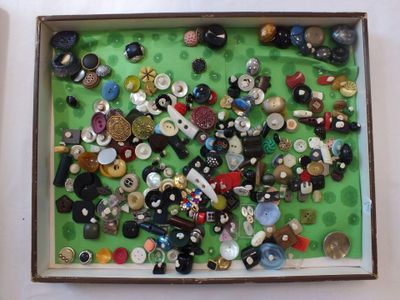 une boîte remplie de boutons assortis posée sur une surface verte