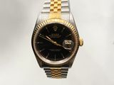 a black and gold rolex watch on a silver and gold bracelet