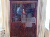 une armoire en bois dans un coin de la pièce, avec une horloge accrochée au mur