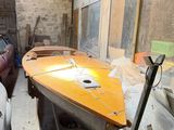 a boat sitting in a room with a lot of stuff on the floor