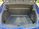 the back of a blue car with its trunk open and luggage in the trunk