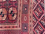 un gros plan d'un tapis rouge et noir posé sur un parquet